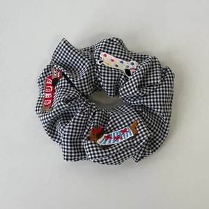 Detailed view of checkered scrunchie with cute embroidered dachshund puppy and colorful bone