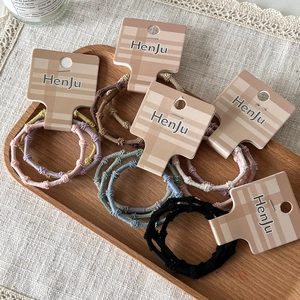 Lot d'élastiques à cheveux tressés haute élasticité multicolores sur plateau en bois