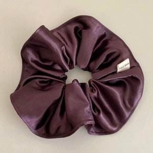 Detail view of smooth satin plum hair scrunchie with a white Hand Made woven label