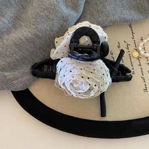 Detail of elegant white lace rose hair claw with black dots on a pearl display tray