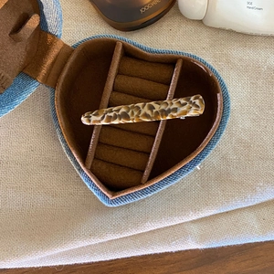 Detail of leopard print acetate hair clip inside a heart-shaped denim jewelry box