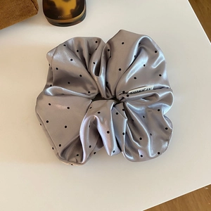 Detailed shot of large satin grey polka dot scrunchie with a soft silky luster finish