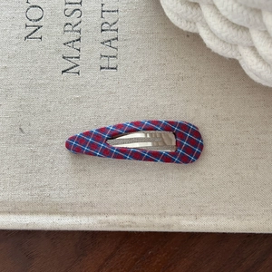 Classic red and blue plaid fabric BB hair clip on a vintage textured book background