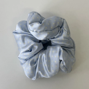 Detail eines hellblauen Scrunchie mit Polka-Dots, Satin-Textur und bauschigem Design