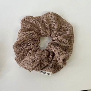 Gros plan détaillé du chouchou en tulle marron avec texture élastique et étiquette
