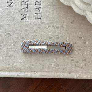 Close-up of a blue and brown plaid fabric hair clip with a stylish rectangular hollow design