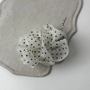 Close-up detail of a French elegant polka dot mesh hair clip with layered chiffon pleats