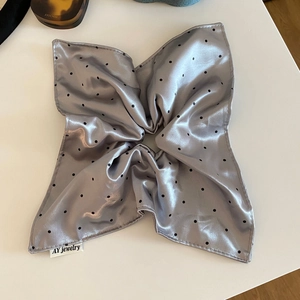 Detail of grey satin polka dot hair scrunchie with silk sheen and branding label