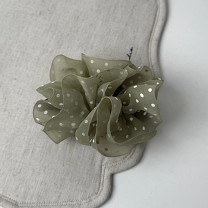Detail of army green organza scrunchie with white polka dots and elegant ruffled texture
