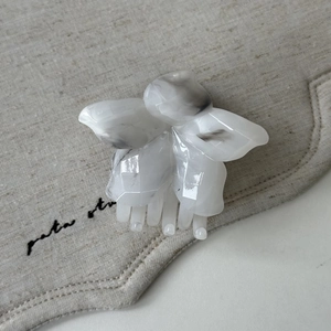 Détail d'une pince à cheveux fleur aux textures marbrées sur fond de tissu en lin