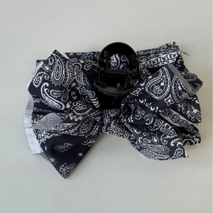 Detail view of large paisley print fabric bow hair claw clip with black plastic base
