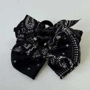 Detail view of the black paisley print fabric bow hair claw clip for women's hairstyle