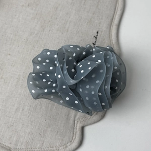 Close-up of grey polka dot mesh scrunchie with soft ruffled fabric on linen mat