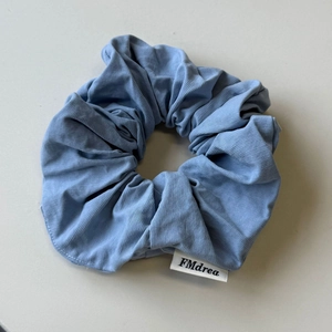 Close-up of Morandi blue scrunchie with fine knitted texture and FMdrea woven label