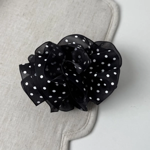 Detail of elegant black and white polka dot mesh fabric flower clip with layered tulle texture