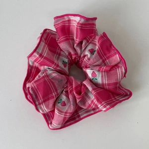 Dettaglio di elastico per capelli a quadretti rosa con ricamo a fragola e cuciture
