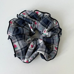 Dettaglio scrunchie a quadretti blu navy con ricamo a fragola e consistenza del tessuto