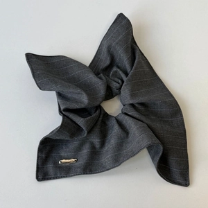Macro view of dark grey striped fabric hair scrunchie with handmade metal tag detail