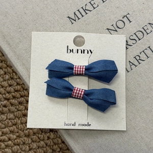 Close-up of denim bow hair clips with red gingham centers on a handmade display card