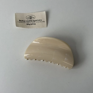 Détail d'une grande pince à cheveux crème avec une finition lisse à texture marbrée