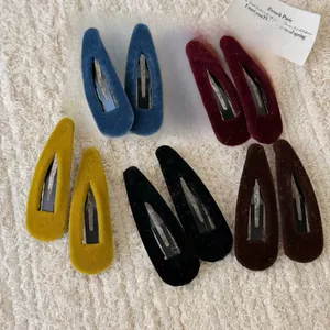 Flat lay of colorful velvet teardrop BB hair clips on beige knitted fabric texture