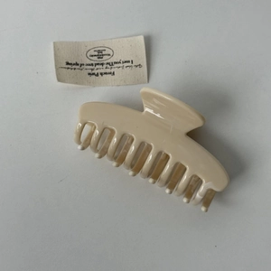 Vue détaillée d'une pince à cheveux beige crème brillante avec un ressort métallique robuste