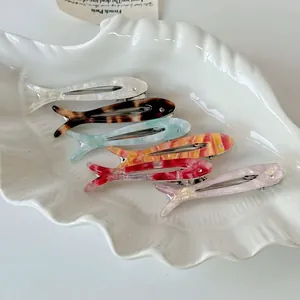 Set of six colorful fish-shaped acetate hair clips with rhinestones in a shell tray