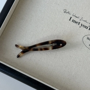 Detailed macro view of fish-shaped acetate clip with tortoise marble pattern and rhinestone