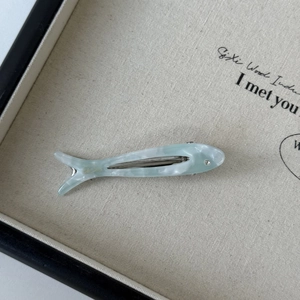 Macro view of mint green fish-shaped acetate hair clip with marble texture and rhinestone