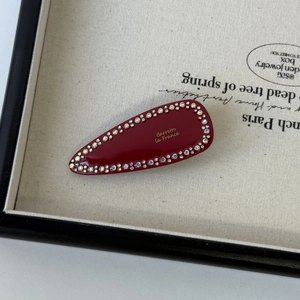 Macro shot of deep red barrette with colorful rhinestones and gold French lettering