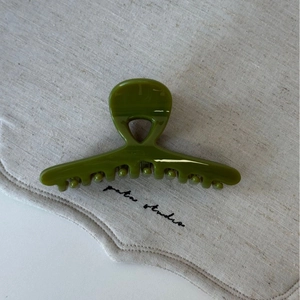 Gros plan d'une pince à cheveux vert olive brillante en acétate avec dents croisées