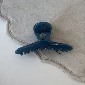 Grande pince à cheveux bleu foncé brillant sur lin montrant les dents et la structure solide