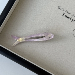 Detailed close-up of fish-shaped acetate hair clip with pearlescent purple finish and rhinestone