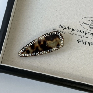 Macro detail of tortoiseshell acetate hair clip with sparkling rhinestones and gold engraving