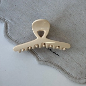 Gros plan sur la pince à cheveux croisée crème brillante sur tissu texturé