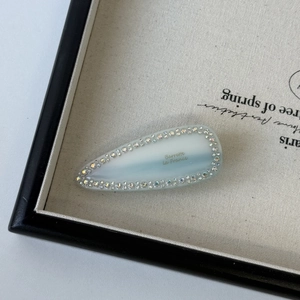 Detail view of a blue gradient hair clip with rhinestone trim and French lettering