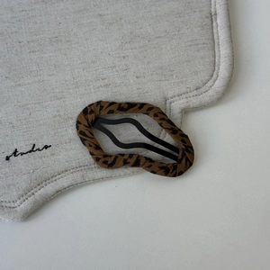 Detail of leopard print fabric hair clip on beige linen cloth with studio embroidery