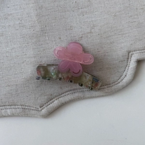 Détail de pince à cheveux fleur avec pétales roses mats et base à paillettes colorées