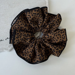 Detailed view of leopard print scrunchie with dark brown pattern and soft fabric texture