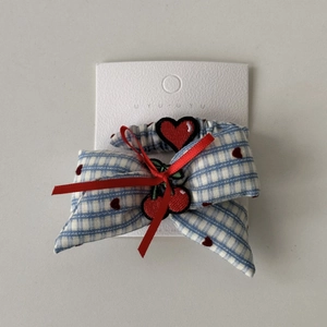 Detail of blue gingham hair scrunchie with heart embroidery and red ribbon on display card