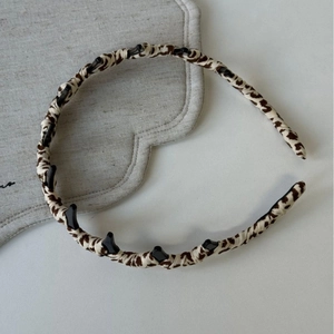Detail of leopard print headband with integrated small hair clips for braided styling