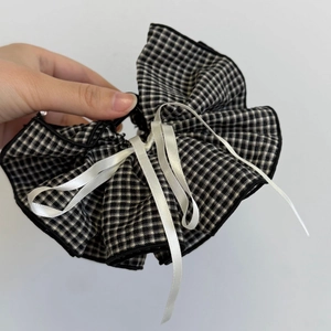 Detail of checkered bow hair claw with elegant white satin ribbons and ruffle edges