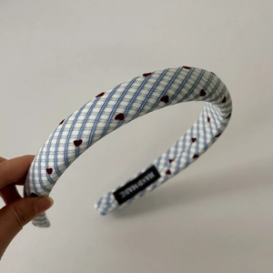 Detail of blue and white gingham hairband with red heart embroidery and handmade tag