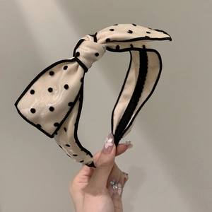 Detail of French polka dot bow headband with creamy fabric and black piping accent