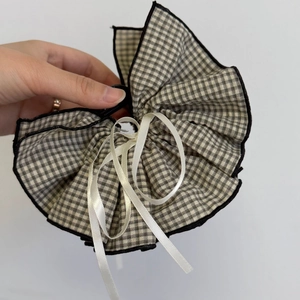 Detail view showing textured gingham fabric layers and white satin ribbon on the hair clip