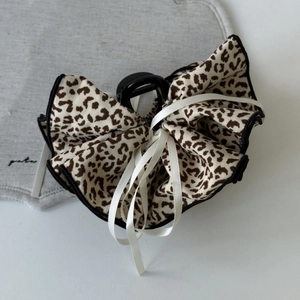 Detail of leopard print bow hair claw with white ribbons and sturdy black plastic clip
