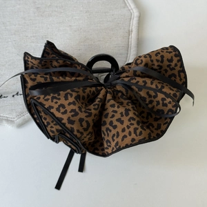 Detail of leopard print bow hair claw clip with black ribbon on a white desk