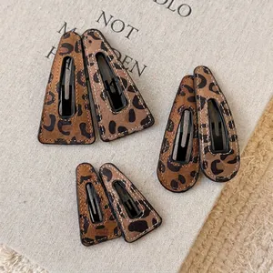 Three pairs of leopard print hair clips in teardrop and triangle shapes on a book