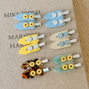 Barrettes à cheveux marguerite en acétate coloré sur fond de livre en lin naturel