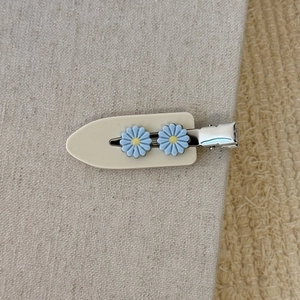 Détail de la pince à cheveux beige avec fleurs de marguerites bleu clair et bec de canard